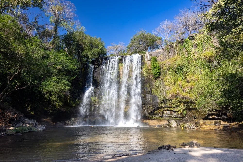 Tourists swimming in the pristine waters of Llanos de Cortés waterfall in Guanacaste.